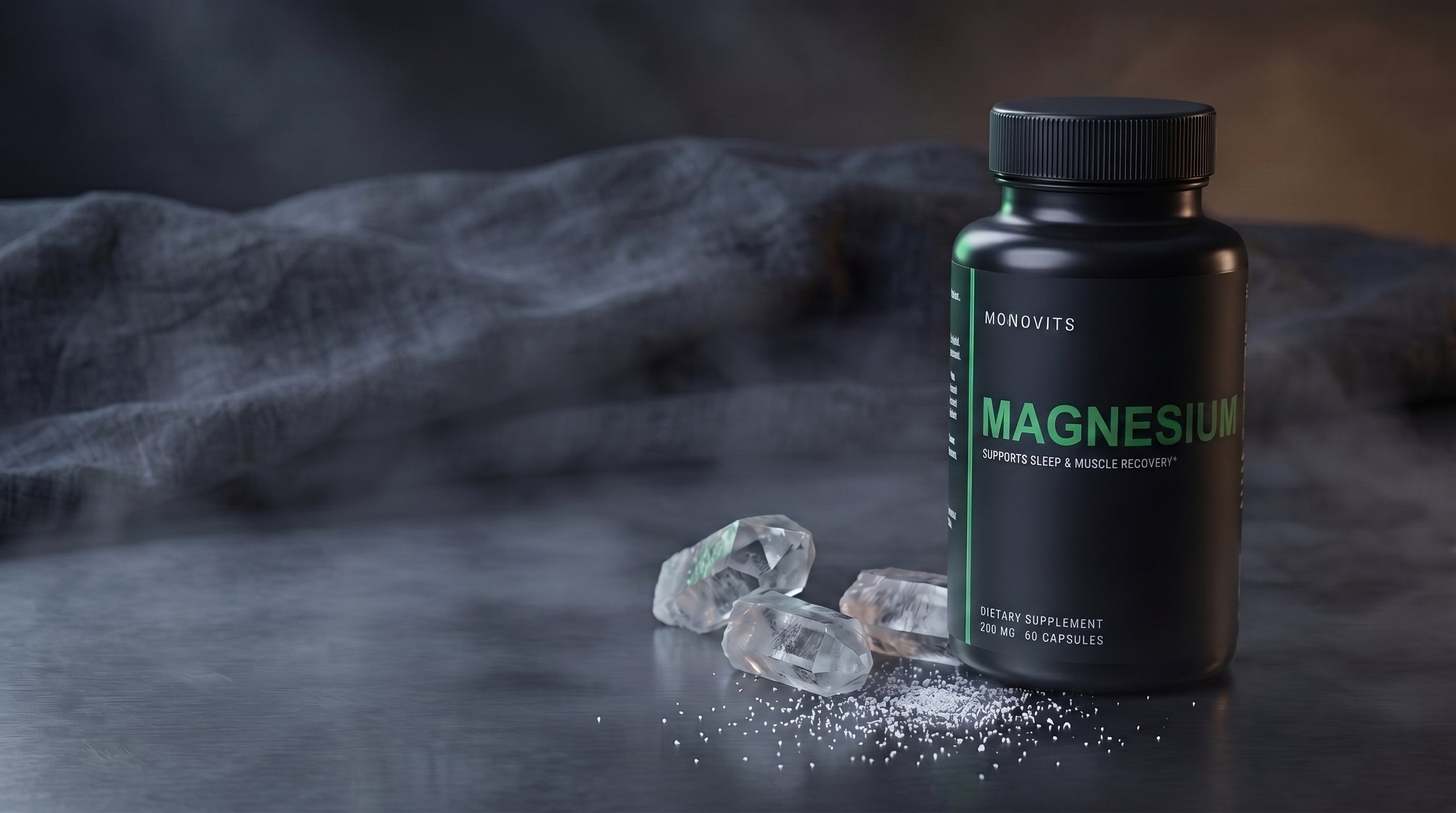 A Monovits Magnesium bottle on brushed dark steel with raw quartz crystals and fine mineral granules.